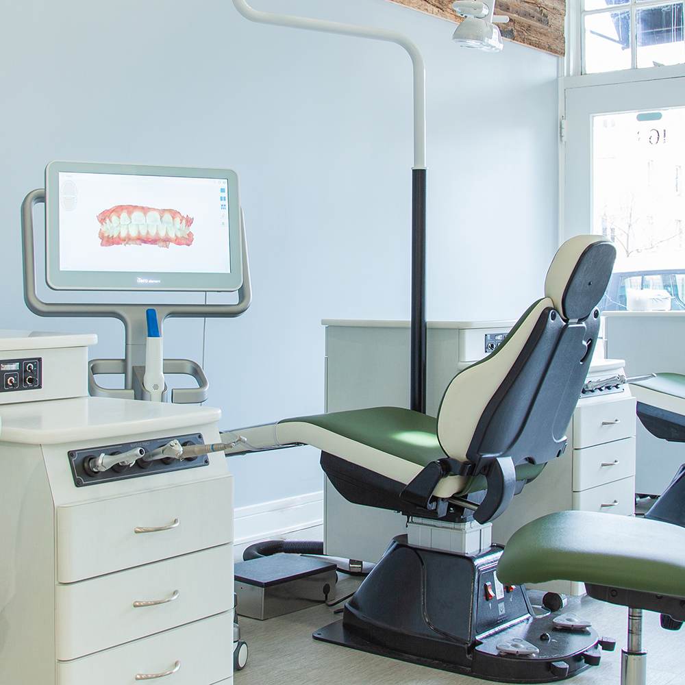 A treatment chair with a screen showing a digital scan of a patient's teeth.